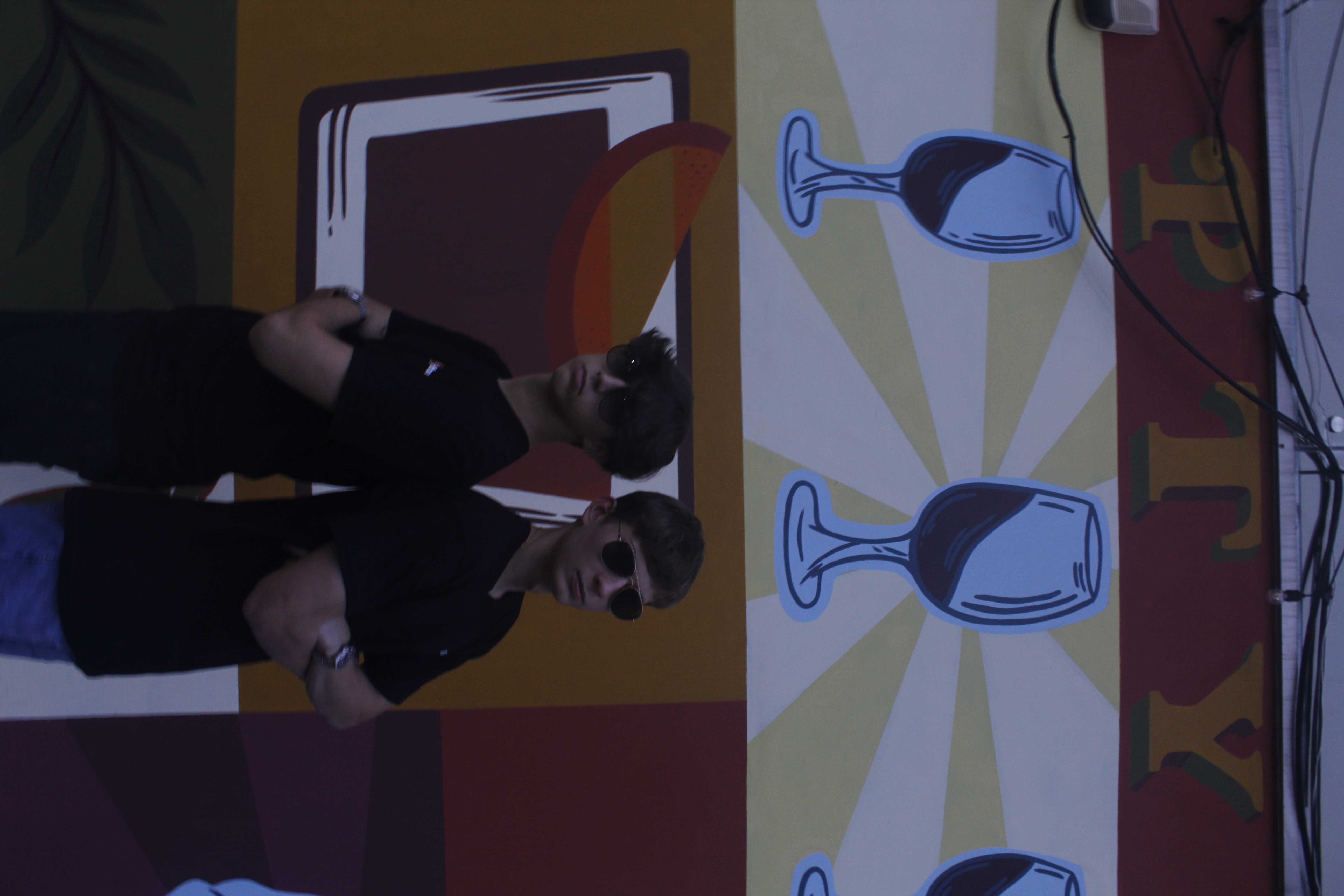 Two people wearing black Liftrank T-shirts in front of a colorful mural